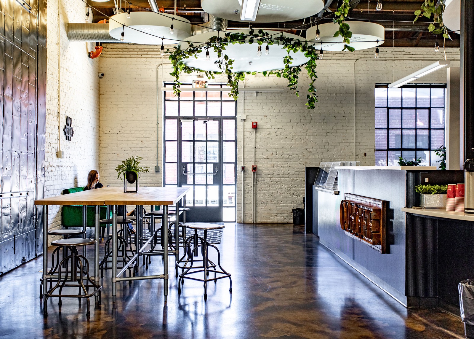 The EC cafe: metal bar stools at a high table, a coffee counter, and one person working alone.
